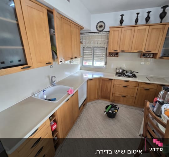 מטבח עם ארונות עץ וכלים על השיש